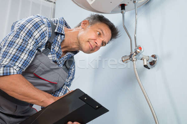 Plumber With Clipboard Looking At Electric Boiler Stock photo © AndreyPopov