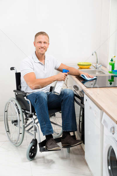 Man On Wheelchair Cleaning Induction Stove Stock photo © AndreyPopov
