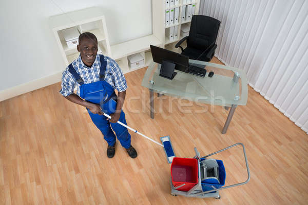 Stock photo: Janitor Cleaning Floor With Wet Floor Sign