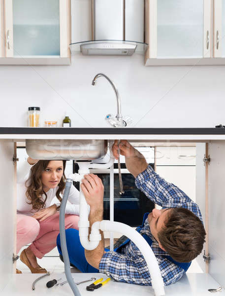 Worker Fixing Sink In Front Of Woman In Kitchen Stock photo © AndreyPopov