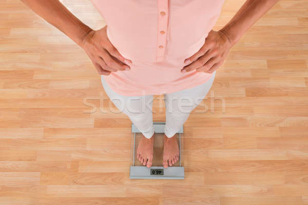 Stock photo: Woman Standing On Weighing Scale