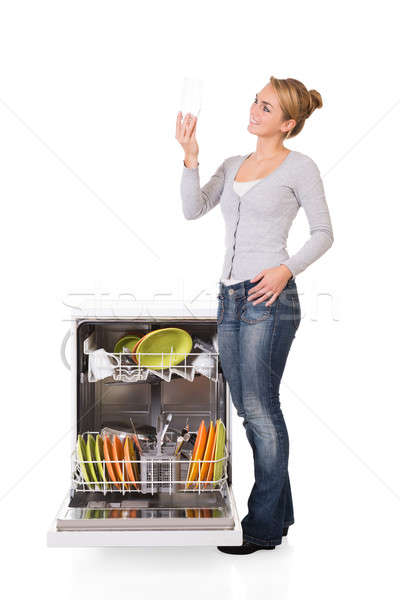 Woman Looking At Clean Glass While Standing By Dishwasher Stock photo © AndreyPopov