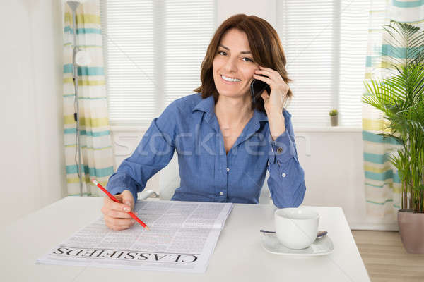 Woman Holding Newspaper While Talking On Mobile Phone Stock photo © AndreyPopov