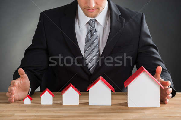 Businessman Shielding House Models Stock photo © AndreyPopov
