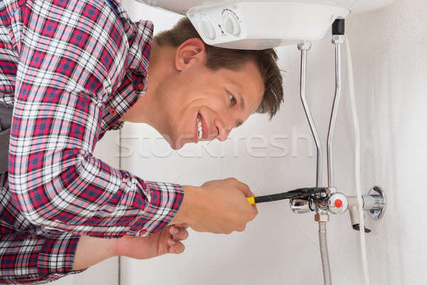 Stock photo: Worker Repairing Electric Boiler With Wrench