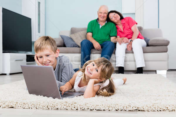 Stock photo: Grandparent Looking At Their Grandchildren Using Laptop