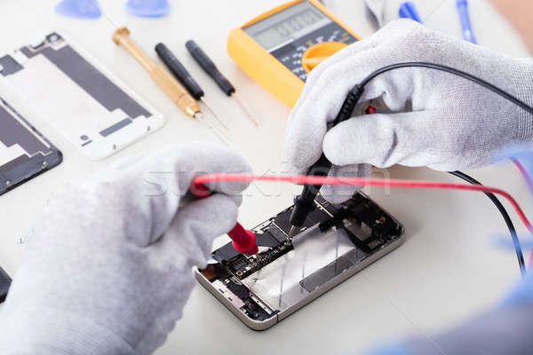 Person Checking Damaged Mobile Phone With Digital Multimeter Stock photo © AndreyPopov