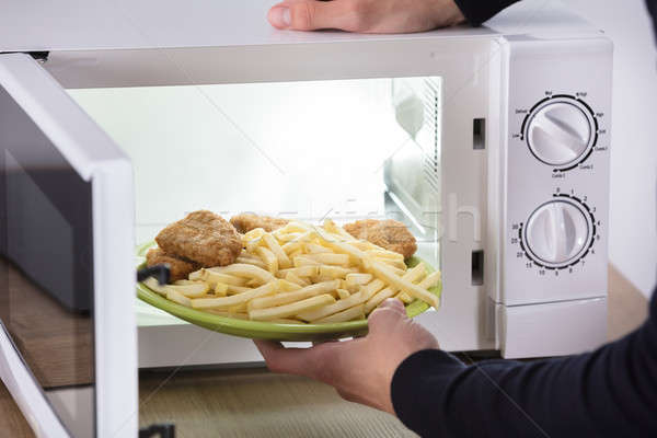 Pessoa frito comida dentro microonda forno Foto stock © AndreyPopov