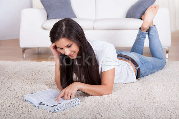 Woman lying on a carpet reading Stock photo © AndreyPopov