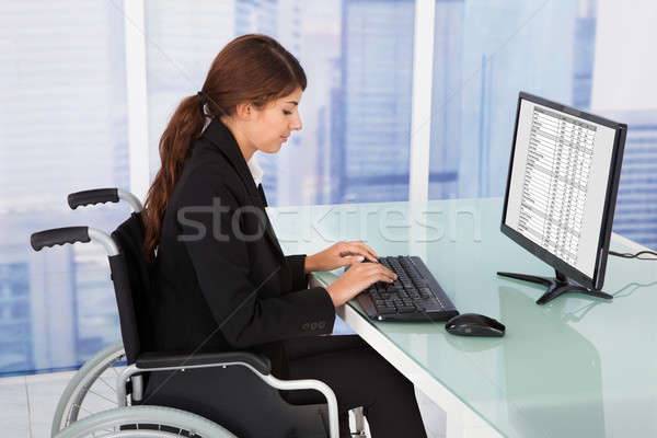 Businesswoman Using Computer While Sitting On Wheelchair Stock photo © AndreyPopov