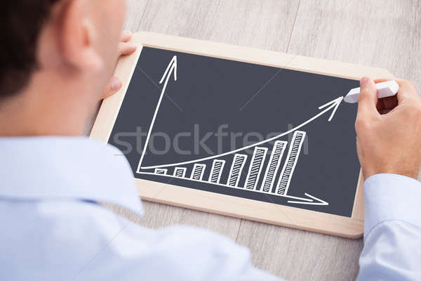 Businessman Drawing Bargraph On Slate At Desk Stock photo © AndreyPopov