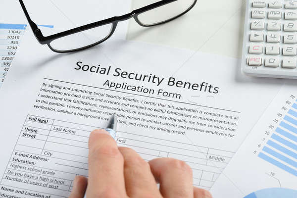 Stock photo: Hand Holding Pen Over Social Security Benefits Form