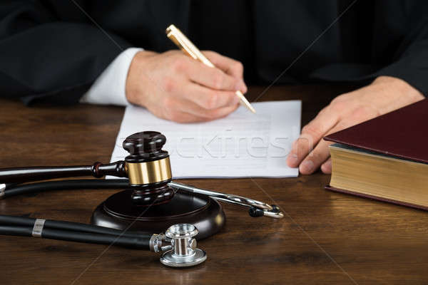 Judge Writing On Document With Mallet And Stethoscope At Desk Stock photo © AndreyPopov