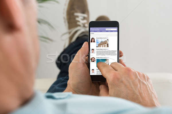 Man Surfing On Social Networking Site Using Cellphone Stock photo © AndreyPopov