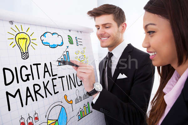 Two Businesspeople Discussing Digital Marketing On Flipchart Stock photo © AndreyPopov