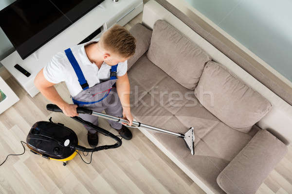 Giovane cleaner divano aspirapolvere view Foto d'archivio © AndreyPopov