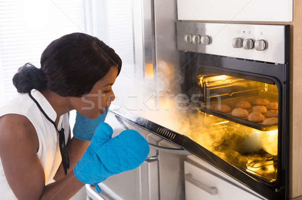 Stock photo: Shocked Woman Looking At Burnt Cookies In Oven
