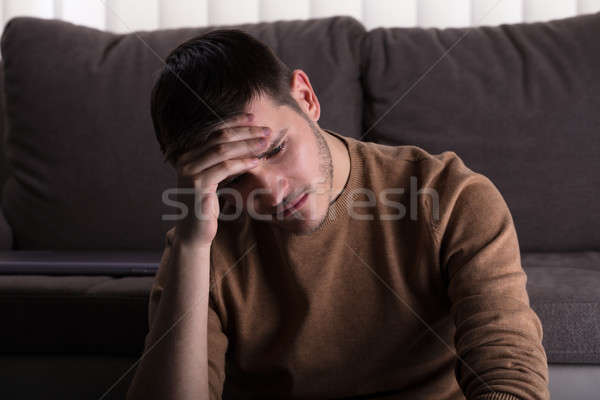 Sad Man Sitting In Front Of Sofa Stock photo © AndreyPopov