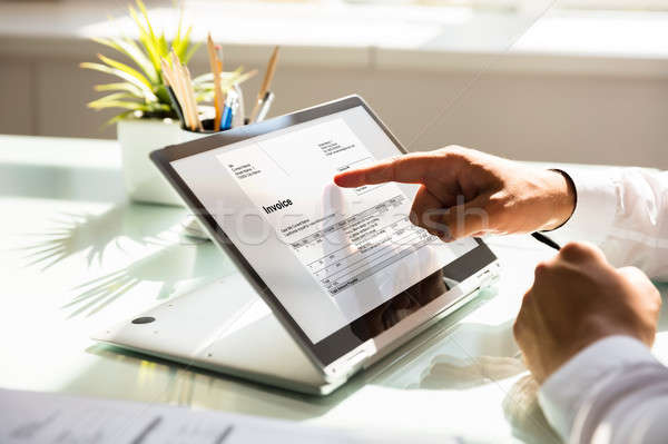 Businessman examining invoice on laptop Stock photo © AndreyPopov