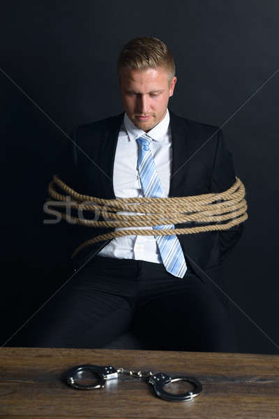 Businessman Tied With Rope Sitting In Front Of Table Stock photo © AndreyPopov