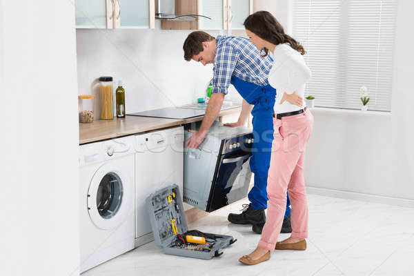 Stock photo: Woman Looking At Male Worker Repairing Oven