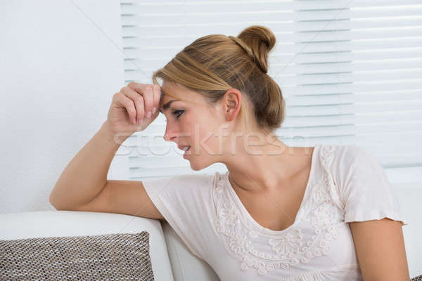Woman Suffering From Headache While Sitting On Sofa Stock photo © AndreyPopov