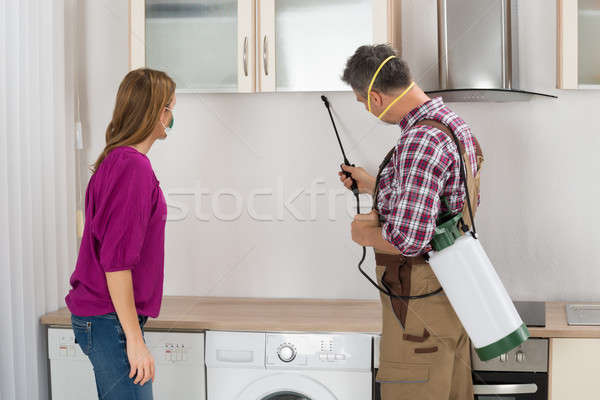 Male Worker Spraying Insecticide Under Cabinet Stock photo © AndreyPopov
