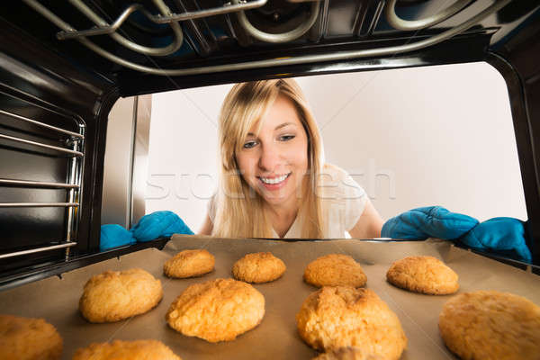 Woman Inserting Cookies Tray In Oven Stock photo © AndreyPopov