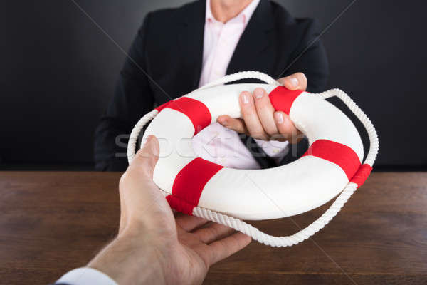 Businessman Passing A Lifebuoy To A Partner Stock photo © AndreyPopov