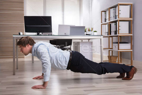 Stock photo: Businessman Doing Push Up In Office