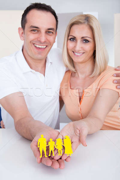 Portrait of happy couple holding family figure cut-out Stock photo © AndreyPopov