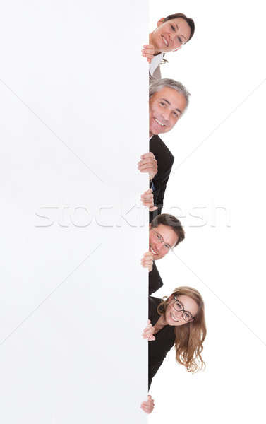 Businesspeople peering around a blank banner Stock photo © AndreyPopov