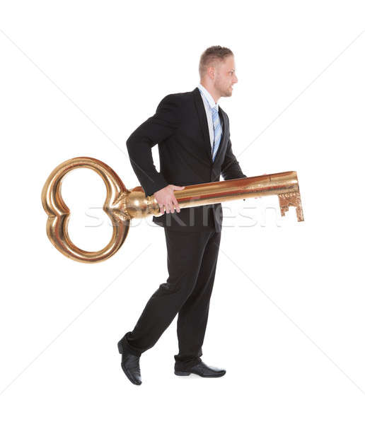 Businessman carrying an old-fashioned large brass key Stock photo © AndreyPopov