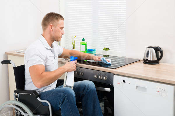 Deficientes homem limpeza fogão jovem cadeira de rodas Foto stock © AndreyPopov