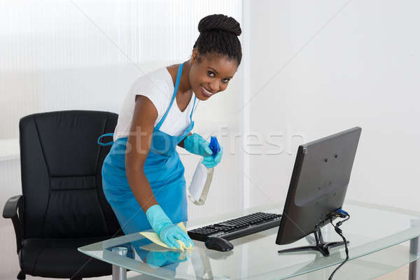 Kobieta czyszczenia biurko szmata uśmiechnięty młodych Zdjęcia stock © AndreyPopov