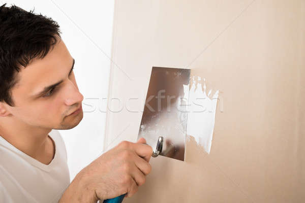 Man Using Putty Knife On White Wall Stock photo © AndreyPopov