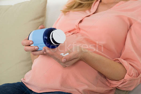 Pregnant Woman Pouring Pills In Hand From Bottle Stock photo © AndreyPopov