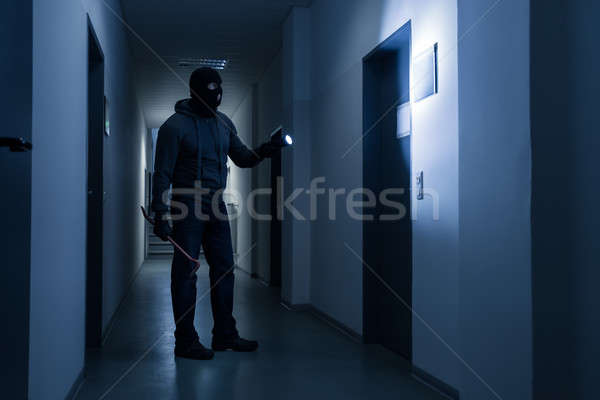 Stock photo: Burglar With Flashlight And Crowbar In Office Building