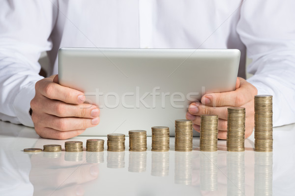 Businessman Using Digital Tablet With Stacked Coins At Desk Stock photo © AndreyPopov