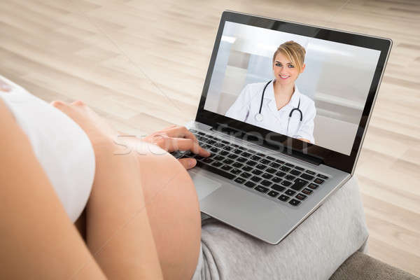 Donna incinta medico laptop seduta divano home Foto d'archivio © AndreyPopov