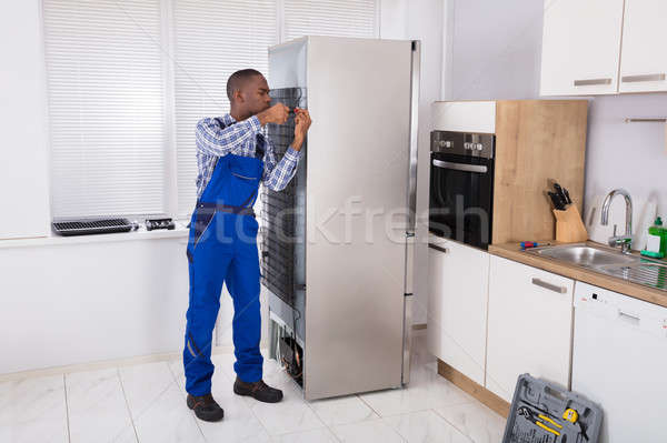 Complessivo lavoro frigorifero cacciavite cucina uomo Foto d'archivio © AndreyPopov