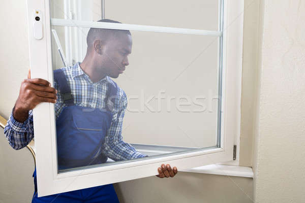 Stock photo: Repairman In Overalls Installing Window