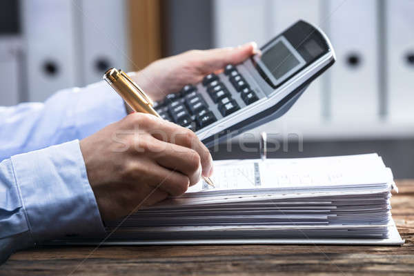 Close-up Of A Businessperson's Hand Calculating Invoice Stock photo © AndreyPopov