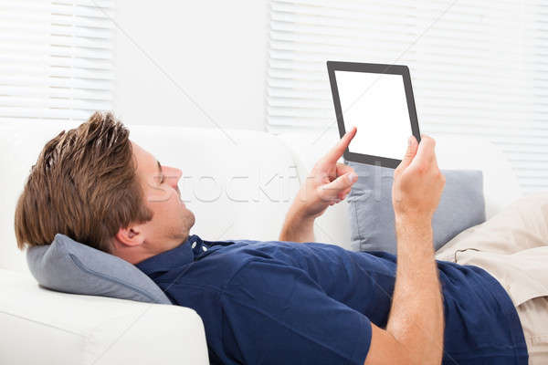 Man Using Digital Tablet With Blank Screen On Sofa Stock photo © AndreyPopov