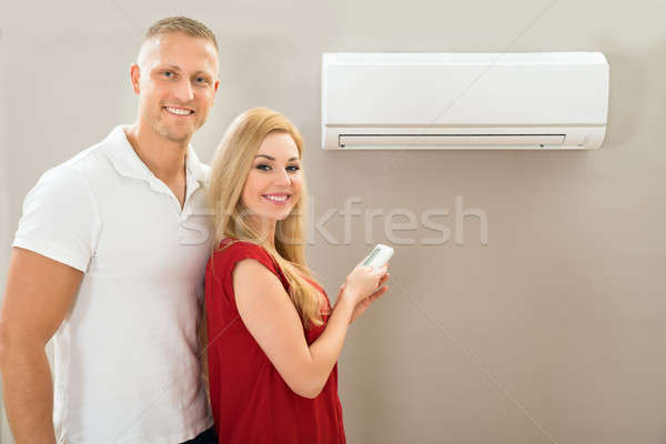 Stock photo: Couple With Remote Control Air Conditioner