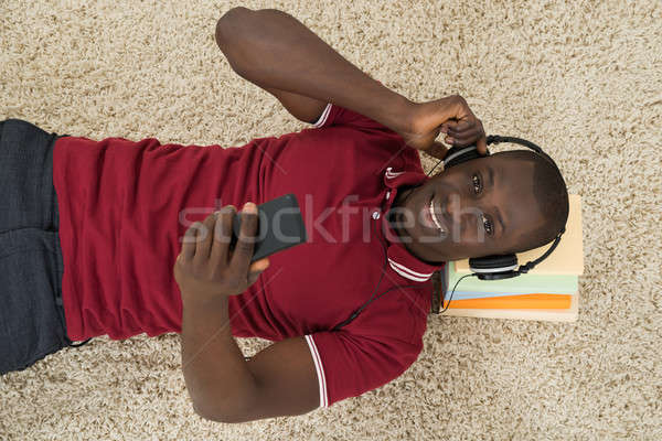Stock photo: Man Lying On Stack Of Books Listening Music On Headphones