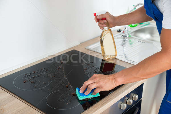 Janitor Cleaning Induction Stove In Kitchen Stock photo © AndreyPopov