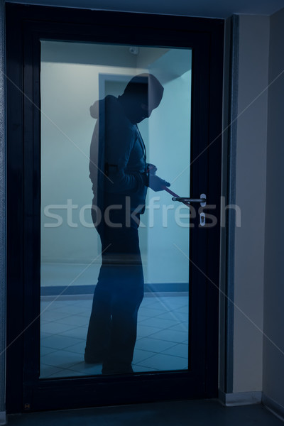 Stock photo: Burglar Using Crowbar To Open Glass Door