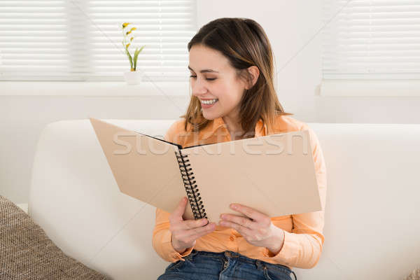 Woman Smiling While Looking At Photo Album Stock photo © AndreyPopov