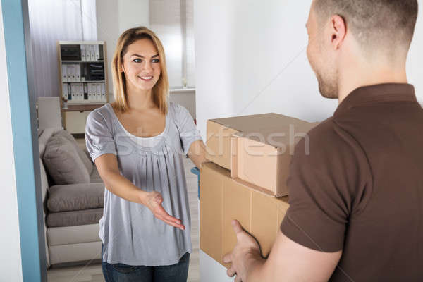 Stock photo: Delivery Man Giving Parcel Box To Young Woman